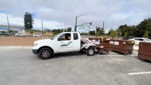 A TrashScouts truck hauling multiple brown dumpsters in Oakland, CA, demonstrating junk removal services.
