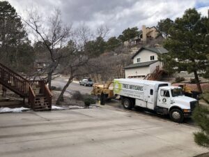 A Tree Artisans truck with a wood chipper parked on a residential driveway, ready for tree service work in Colorado Springs, CO.