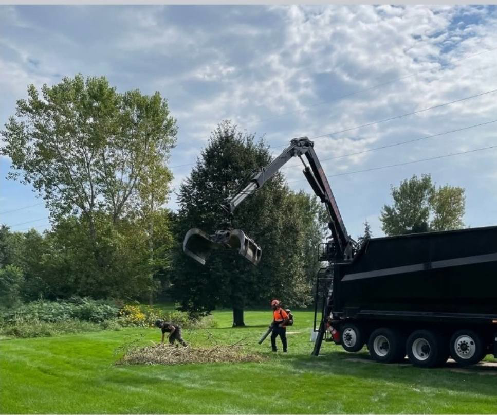 Tree service crew cleaning up debris with a grapple truck for Precision Landscape and Tree in Little Canada, MN.