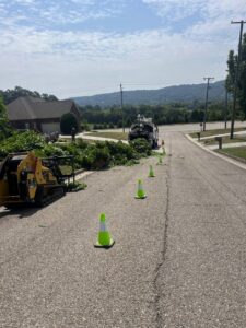 Tree debris and equipment, including a skid steer, on a residential street after tree work by Elite Tree Service in Knoxville, TN.