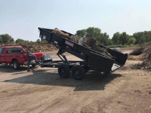 A dump trailer filled with tree debris being unloaded by Rothman Tree Service in Des Moines, IA.