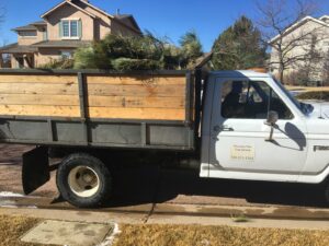 A Mountain Men Tree Service truck loaded with cut tree branches for debris removal in Denver, CO.