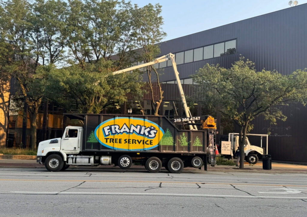 Frank's Tree Service truck and chipper on a street while workers prune trees in Davenport, IA.