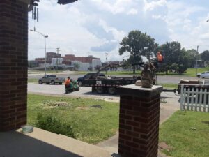 A tree removal and cleanup crew with a crane truck and mini skid steer working on a residential street for Gray's Tree and Crane Service in Evansville, IN.