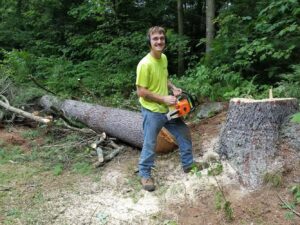 A tree surgeon from Bryan McFadden LLC Tree Surgeon with a chainsaw after a tree removal job in Auburn, ME.