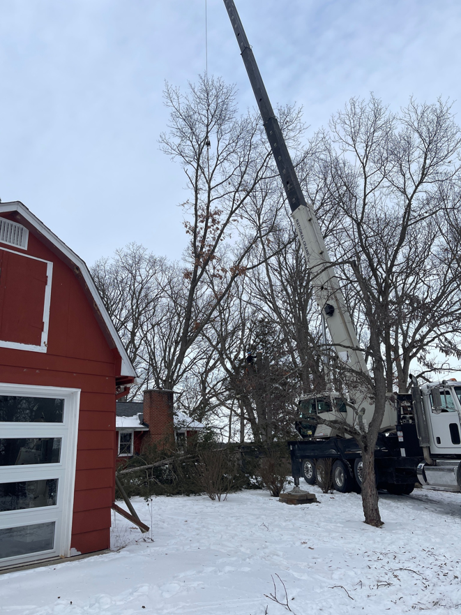 A large crane assisting with tree removal near a house by J's Tree Trimming and Removal, Inc. in Ann Arbor, MI.