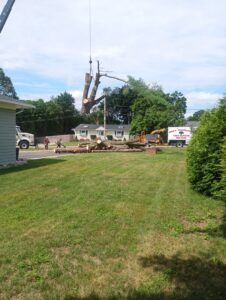A crane lifting a large tree trunk section during a tree removal job by Mike's Professional Tree Service in Coventry, RI.