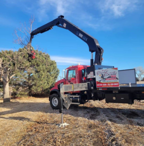 A crane truck from Broken Branch Tree Removal actively removing a tree branch in Broadalbin, NY.