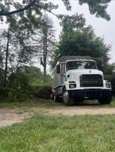 A tree service truck parked while a crew member works high in a tree for EK Tree Service in Lancaster, PA.