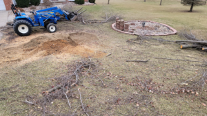 A tree removal site with a tractor, piles of wood chips, and cut branches on a lawn by AJ'S Stump Grinding in Bauxite, AR.