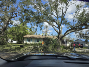 A tree service crew performing storm cleanup and tree removal near a house for M.L tree service in Dayton, OH.