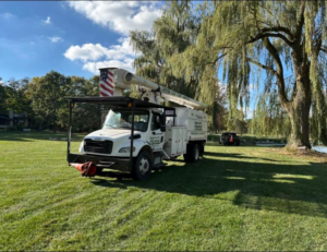 A tree service bucket truck parked on a lawn by Upper Cut Tree Service, LLC in Williamston, MI