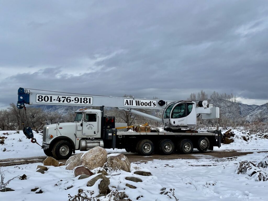 A tree service crane truck parked in a snowy landscape, ready for work by All Wood's Tree Service in Ogden, UT.