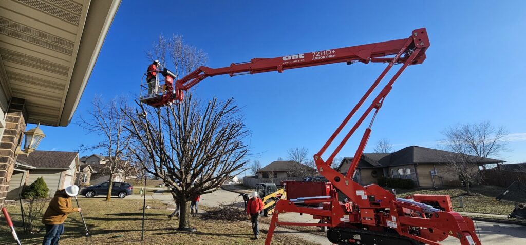 A tree service crew with a spider lift and skid steer working on a residential street for Braik's Tree Care in Columbia, MO.