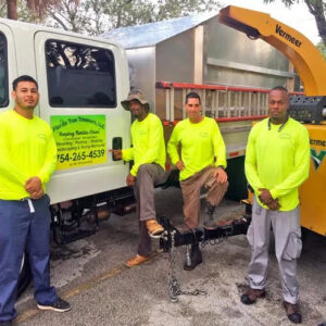 A professional tree service crew standing in front of their chipper truck, representing Florida Tree Cutters in Fort Lauderdale, FL