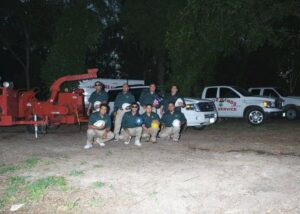 The Good Hands Tree Service crew posing with their equipment and trucks on a job site in Dallas, TX