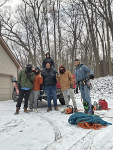 Leiva tree Service crew with chainsaws and ropes on a snowy job site in Detroit, MI, ready for work.