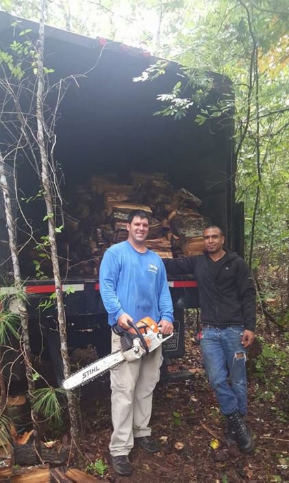 Sharp Tree Service crew members with a chainsaw and a truck full of firewood after a tree service job in Cumming, GA.