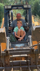 Tree service crew member operating a skid steer with grapple attachment for Treeality Tree Technologies LLC in Savannah, GA.