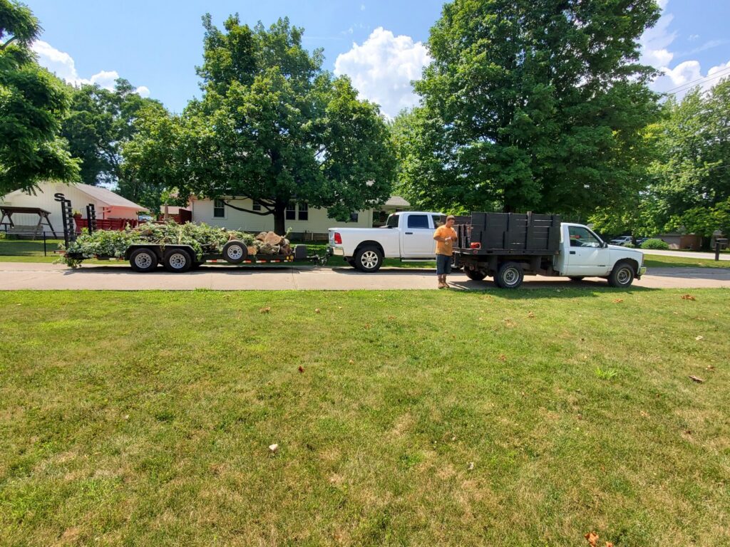A tree service crew with trucks and a trailer loaded with tree debris after a job by Canter Tree & Stump Solutions in Indianapolis, IN.
