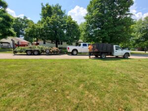 A tree service crew with trucks and a trailer loaded with tree debris after a job by Canter Tree & Stump Solutions in Indianapolis, IN.