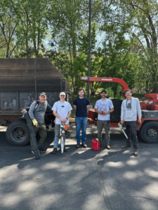 The Rooted Treeworks crew stands with their wood chipper and dump truck after a job in Plymouth, MN.