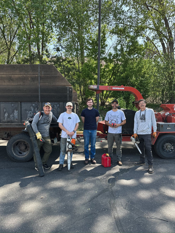 The Rooted Treeworks crew stands with their wood chipper and dump truck after a job in Plymouth, MN.