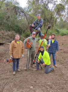 A professional tree service crew with chainsaws and climbing gear after clearing an area for GrowGreen Professional Tree Service in Baton Rouge, LA.