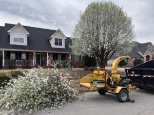 A tree service crew using a wood chipper and dump trailer to process branches for Liberty Tree in Fort Smith, AR.