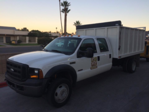 A white tree service dump truck with the business logo for Creative Tree Care, LLC in Phoenix, AZ.