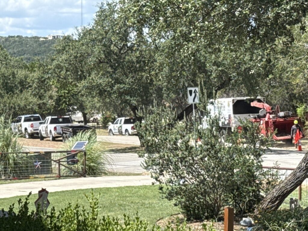 Tree service equipment including trucks and a wood chipper with crew members from S.A. Total Tree Service in San Antonio, TX
