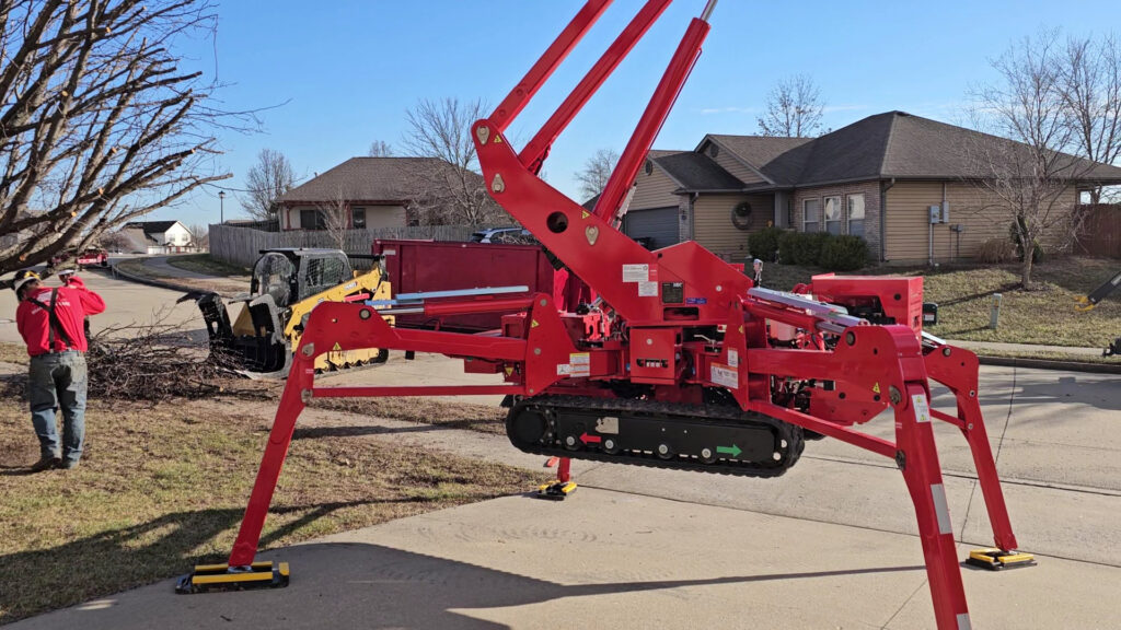 Tree service equipment, including a spider lift and skid steer, with debris on the ground for Braik's Tree Care in Columbia, MO.