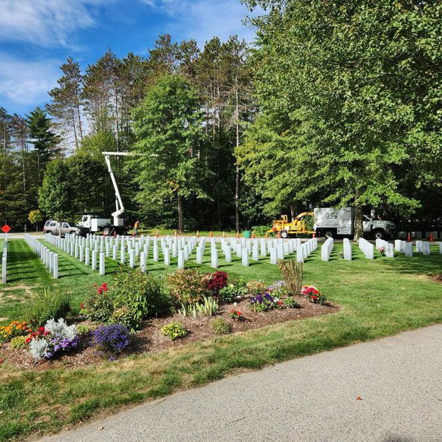 Tree service equipment, including a bucket truck and chipper, parked near trees by Collins Tree Service, Inc. in Hooksett, NH.