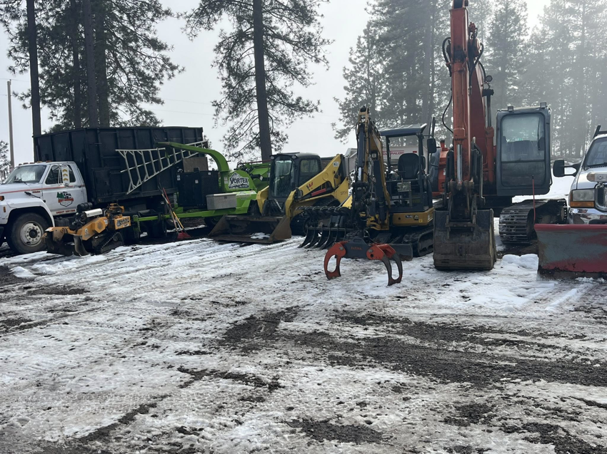 Heavy tree service equipment, including a chipper and excavators, parked in the snow for Hiatt Services in Spokane, WA.