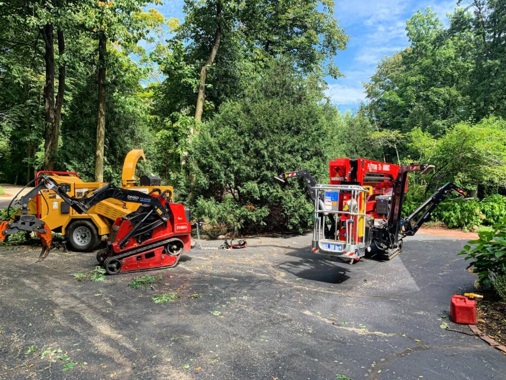 Tree service equipment, including a wood chipper and tracked lift, parked on a residential driveway for Lake Forest Tree Service LLC in Milwaukee, WI.
