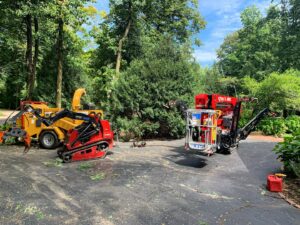 Tree service equipment, including a wood chipper and tracked lift, parked on a residential driveway for Lake Forest Tree Service LLC in Milwaukee, WI.