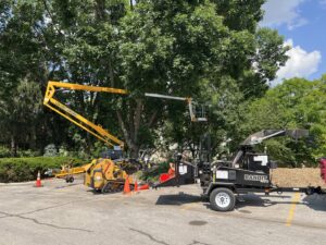 Tree service equipment including a bucket lift, mini skid steer, and wood chipper set up for a job by JN Services LLC in Des Moines, IA.