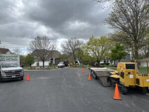 Wildwood Tree Service equipment, including a truck, chipper, and mini skid steer on a trailer, set up on a residential street in Elgin, IL.