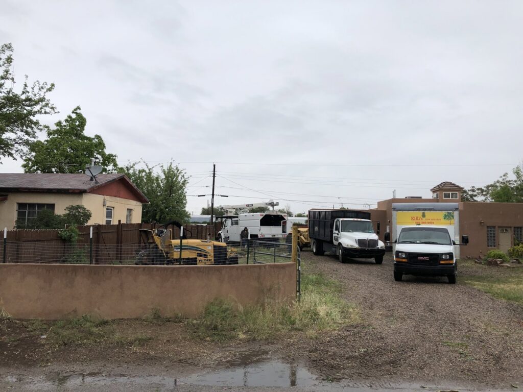 Multiple Kiki's Tree Service vehicles and equipment parked at a residential job site in Albuquerque, NM.