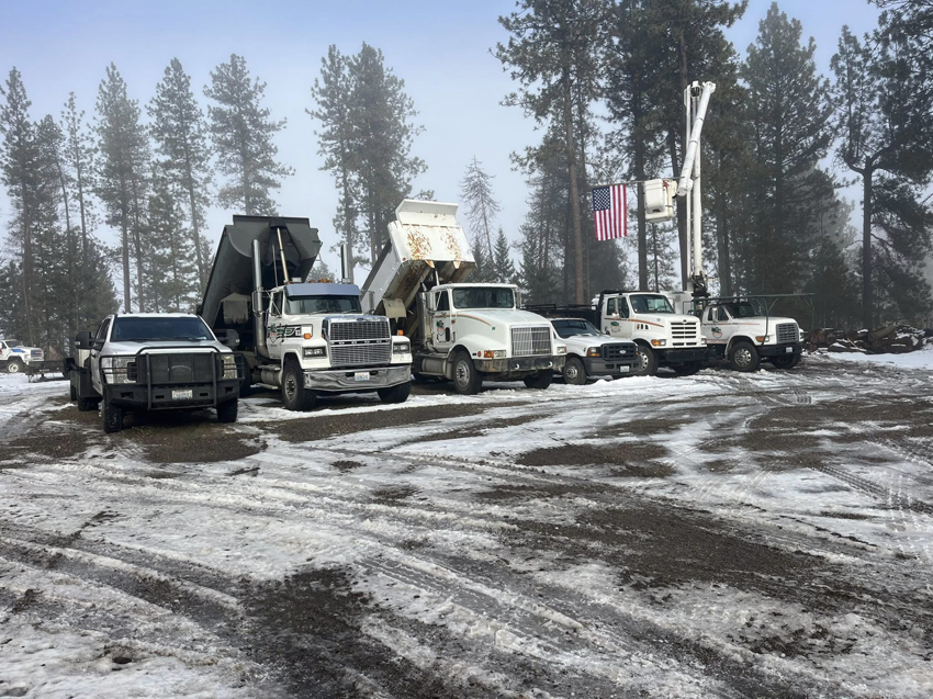 A fleet of tree service trucks, including dump trucks and a bucket truck, ready for work at Hiatt Services in Spokane, WA.