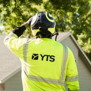 A YTS Companies tree service professional wearing a safety helmet and high-visibility shirt, looking at trees in Maple Grove, MN