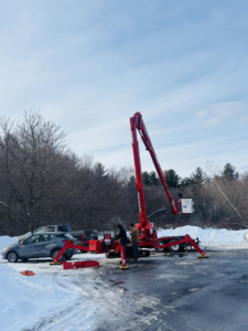 A red spider lift and crew setting up for tree service work in a snowy area by ArbormaxX LLC in Winfield, WV