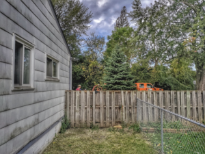 A tree service truck and crew working on tree removal in a residential backyard by Good Fellers Tree Services in Westland, MI.