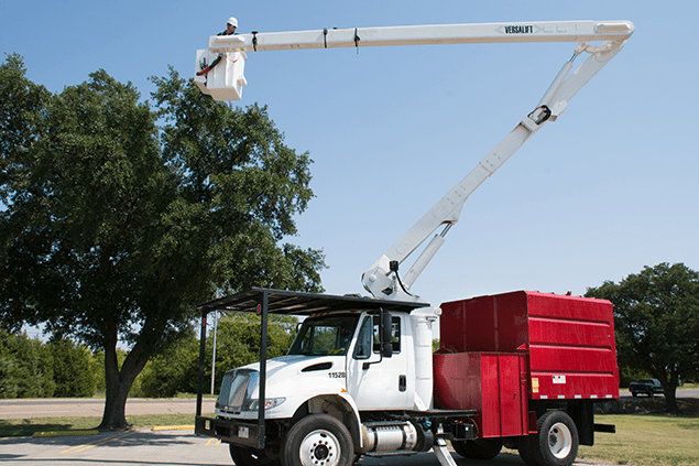 A tree service truck with an extended bucket lift and a worker, ready for tree trimming by Peoria Tree Experts in Peoria, IL.