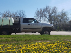A flatbed truck with chemical tanks, branded for tree, lawn, and snow services by The Cavalry LLC in Havre, MT.