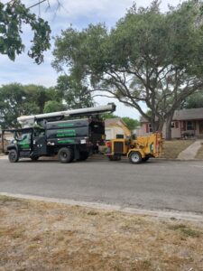 A C & N Tree Service truck with a bucket lift and wood chipper, ready for tree removal in Corpus Christi, TX.