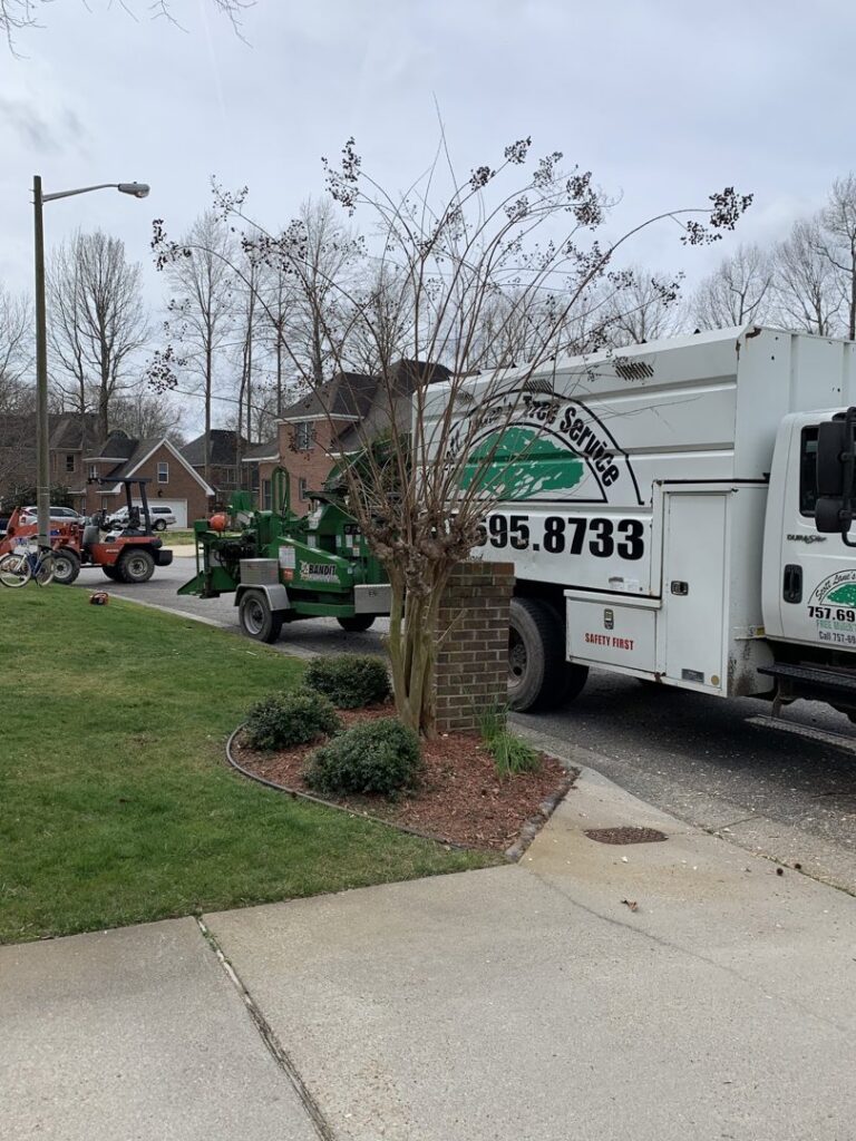 A tree service truck with a wood chipper attached, parked on a residential street by Scott Lanes Tree Service in Chesapeake, VA.