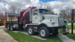 A tree service truck with a crane and a wood chipper on a residential driveway by Ecotree Services LLC in Lorain, OH.