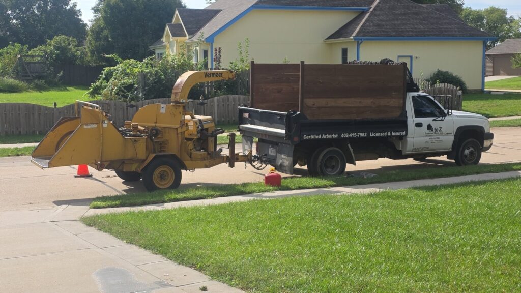 A tree service truck with a wood chipper attached, branded A to Z Trees and More LLC, parked in Omaha, NE.