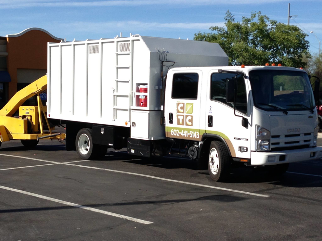 A white tree service truck with a wood chipper attached, ready for work by Creative Tree Care, LLC in Phoenix, AZ.